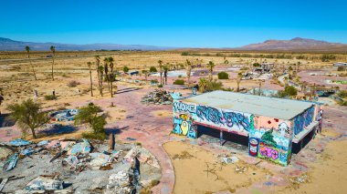 Kaliforniya 'daki terk edilmiş Dolores Gölü su parkının havadan görünüşü. Etrafı çöl manzarası ve parlak güneş ışığı altındaki kalıntılarla çevrili binalara renkli graffitiler konuyor..