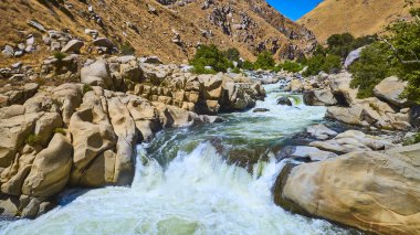 Kern Nehri, Sequoia Ulusal Ormanı 'ndaki engebeli tepeler ve yeşil ağaçlarla çevrili dramatik kayalık çağlayanlardan geçiyor..