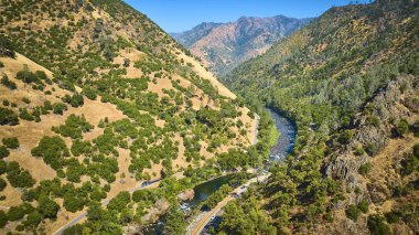 Kaliforniya 'daki Merced Nehri' nin havadan görünüşü Yosemite Ulusal Parkı 'nda altın tepeler ve yemyeşil ormanlarla çevrili engebeli dağlar ve görülebilir dolambaçlı yollarla dolu açık bir günde..