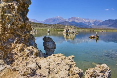 Kaliforniya 'daki Mono Gölü' nün durgun mavi sularından yükselen Tufa oluşumları Lee Vining yakınlarındaki Sierra Nevada dağlarıyla aydınlık bir yaz gökyüzünün altında gerçekleşiyor..