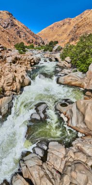 Kern Nehri 'nin Sequoia Ulusal Ormanı' ndaki kayalık şelalelerden ve engebeli altın tepelerden parlak bir günde akan hava manzarası..