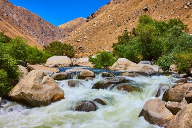 Şelale gibi akan sular, yeşil ağaçlar ve engebeli tepelerle çevrili Kern Nehri 'ndeki kayaların üzerinden akar. Sequoia Ulusal Ormanı' ndaki berrak mavi gökyüzünün altında..