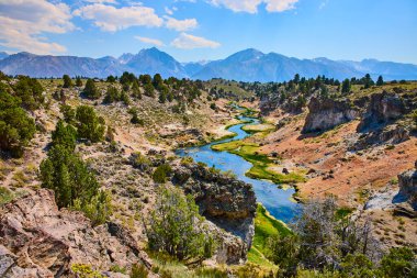 Bereketli kanyon duvarları ve Sierra Nevada dağları ile çevrelenmiş California Mammoth Gölleri yakınlarındaki Hot Creek Jeolojik Alanı 'ndan akan dolambaçlı bir nehir..