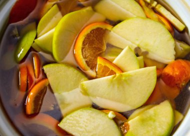 Alkollü içki taze elma, portakal ve mandalina infüzyon. meyve dilimleri bir tencerede dilimlenmiş.