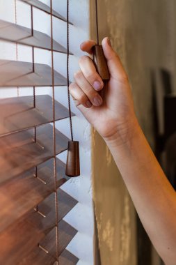 Kadının sağ el ahşap kepenkleri denetim dizelerinden biri üstünde belgili tanımlık pencere tutar.