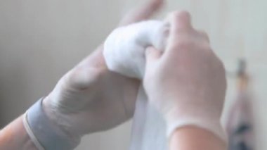eldiven bir doktor ellerinin yakın çekim bir rulo içine tıbbi pamuk yün katlayarak. ses yok.