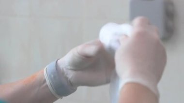 eldiven bir doktor ellerinin yakın çekim bir rulo içine tıbbi pamuk yün katlayarak. ses yok.
