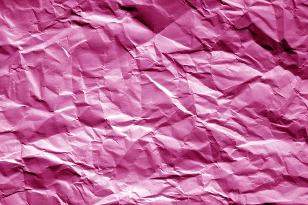 Crumpled sheet of paper in pink tone. Abstract background and texture for design.