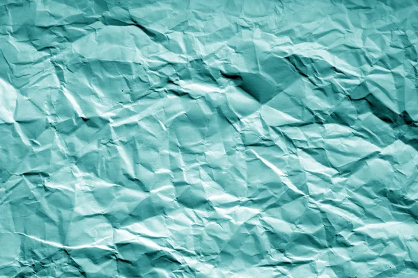 Crumpled sheet of paper with blur effect in cyan tone. Abstract background and texture for design.