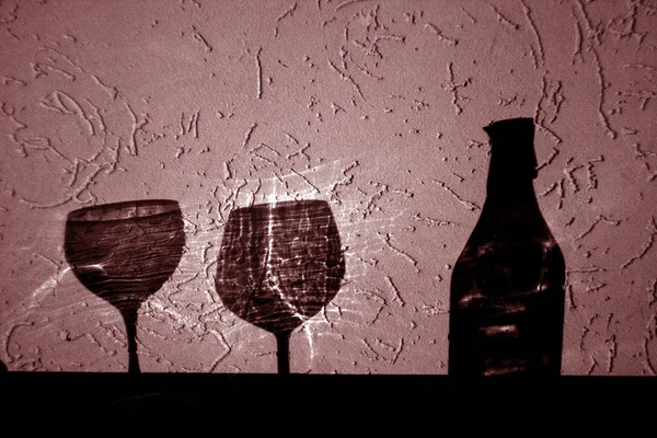 wine bottle and two glasses shadow in red. Abstract backround and view