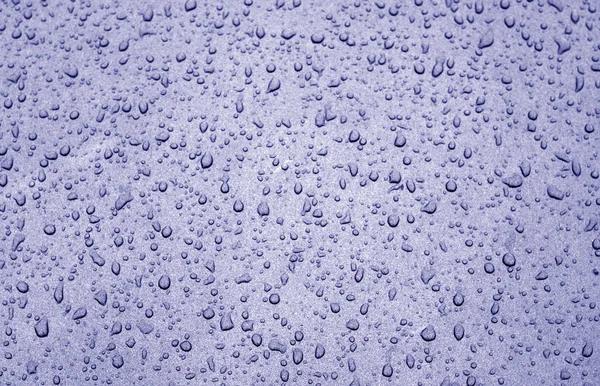 Water drops on car surface in blue tone. Abstract background and texture for design.