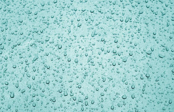 Water drops on car surface in cyan tone. Abstract background and texture for design.