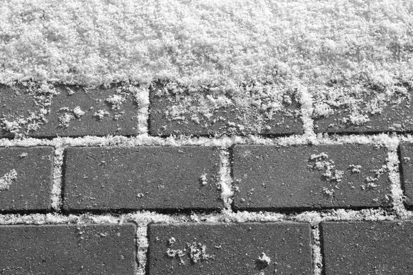 Snow on urban pavement in black and white. Seasonal background texture for design.