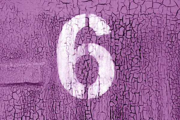 Number 6 in stencil on grungy metal wall in purple tone.