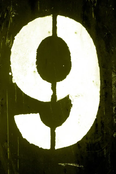 Número 9 em estêncil na parede de metal em tom amarelo . — Fotografia de Stock