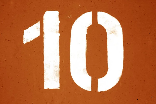 Número 10 em estêncil na parede de metal em tom laranja . — Fotografia de Stock