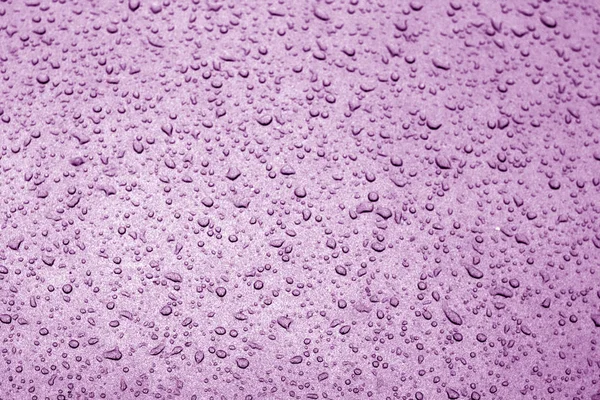 Vatten droppar på bil yta i lila ton. — Stockfoto