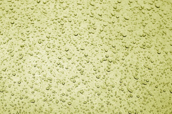 Water drops on car surface in yellow tone.