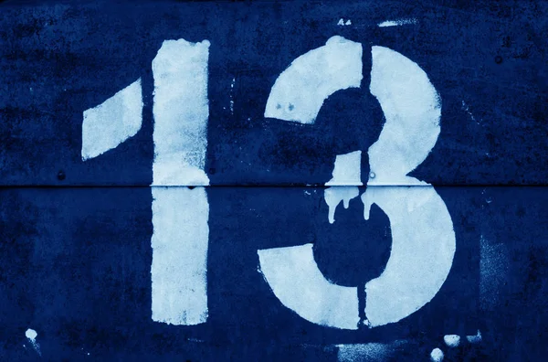 Número 13 em estêncil na parede de metal em tom azul marinho . — Fotografia de Stock