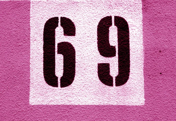 Numer 69 na ścianie cementowej we wzorniku w różowym odcienia. — Zdjęcie stockowe