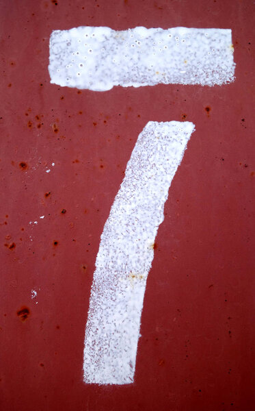 Number 7 in stencil on red metal wall.
