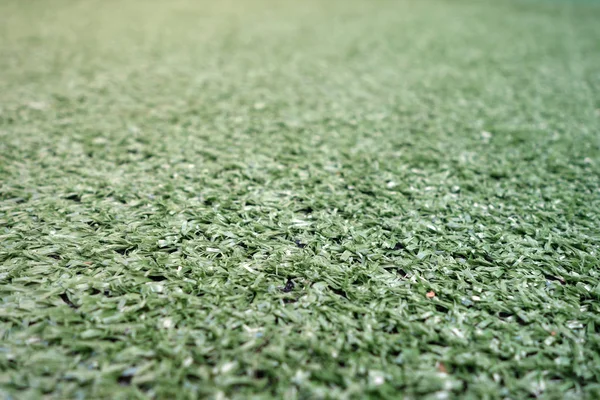 Artificial green color grass with blur effect.