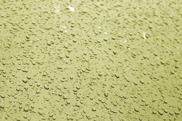 Wassertropfen in gelbem Ton auf der Autooberfläche. — Stockfoto