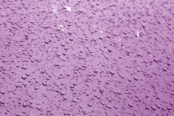 Wassertropfen in violettem Ton auf Autooberfläche. — Stockfoto