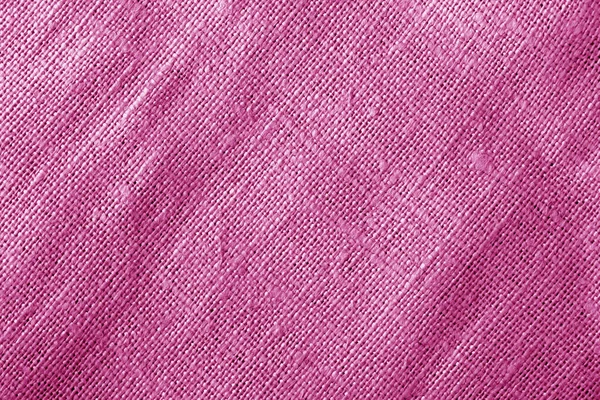 Tela de tul rosa arrugada y comprimida sobre una superficie blanca de cerca