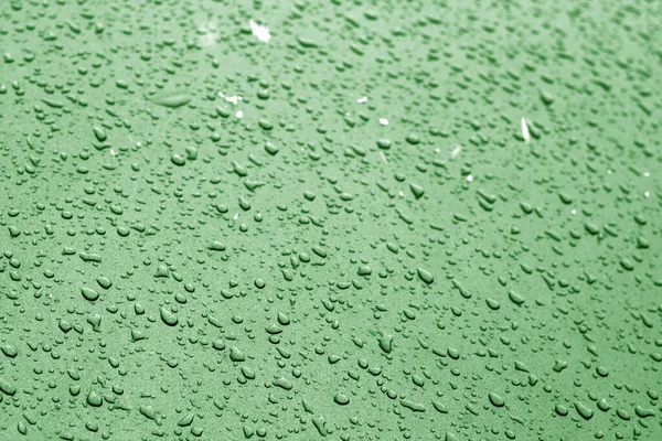 Water drops on car surface in green tone.