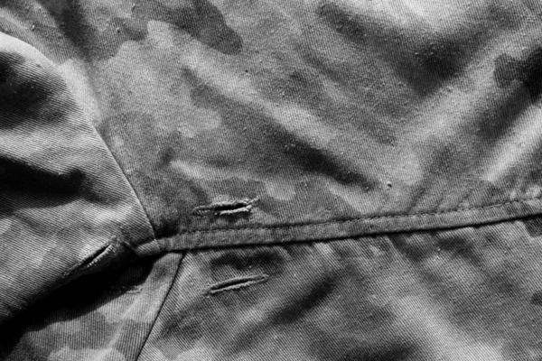 Old military camouflage cloth with holes in black and white. — Stock Photo, Image