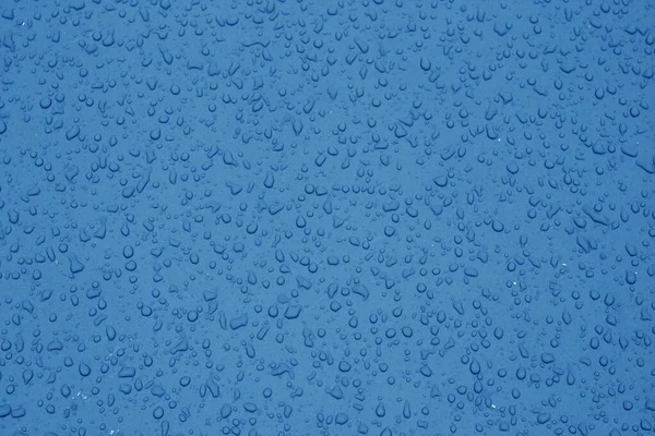 Vatten droppar på bilens yta i marinblå ton. — Stockfoto