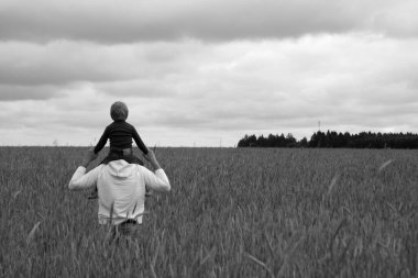 İnsan ve çocuk buğday tarlasında ve bulutlu gökyüzünde. Aile geçmişi