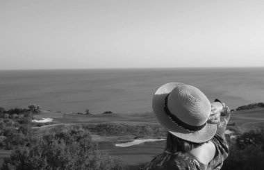 Hasır şapkalı kız golf sahasına ve denize bakıyor. Turizm ve tatil.                     