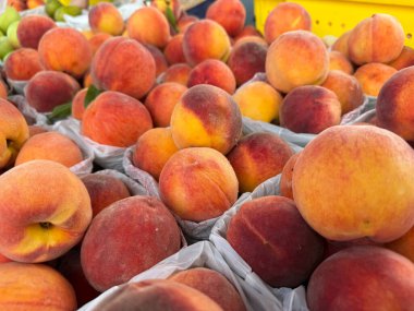 Canlı şeftaliler, Hollanda, Michigan 'daki çiftçi pazarında sepetleri dolduruyor ve canlı bir yaz öğleden sonrasında yerel ürünleri sergiliyorlar. Ziyaretçiler mevcut çeşitliliğin ve tatların keyfini çıkarıyorlar.