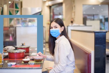 Coronavirus salgını nedeniyle şehir kapatılırken, restoranda sosyal mesafe protokolü olan bir kadın yemek yiyor. 