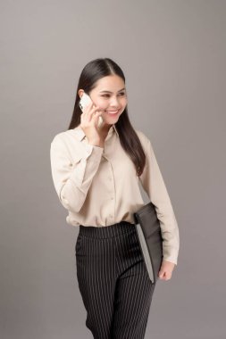 Genç güzel bir kadının portresi gri arka planda cep telefonu kullanıyor. 