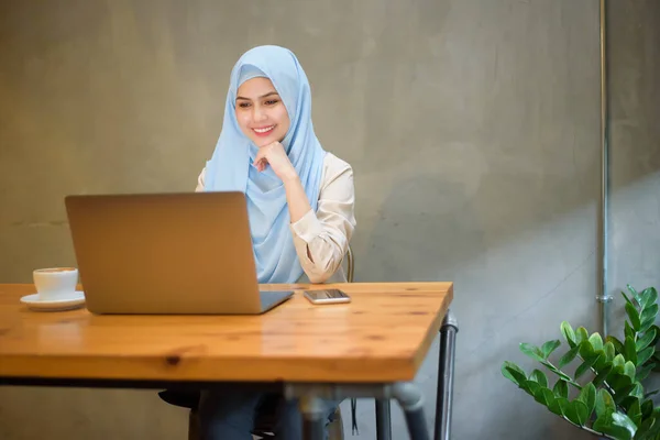 Muslim woman with hijab is working with laptop computer in coffee shop