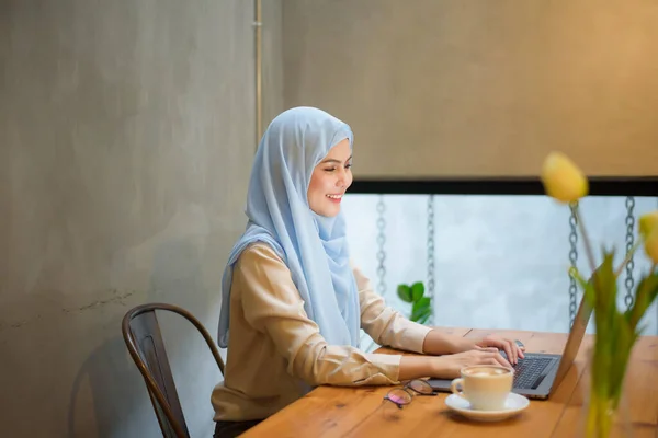 穆斯林妇女头戴头巾 在咖啡店用手提电脑工作 — 图库照片