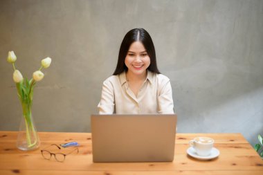 Güzel bir iş kadını kafeteryada dizüstü bilgisayarla çalışıyor.