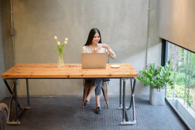 Güzel bir iş kadını kafeteryada dizüstü bilgisayarla çalışıyor.
