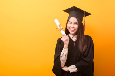 Mezuniyet elbisesi içinde mutlu bir kadının portresi sarı arka plan üzerine eğitim sertifikası taşıyor. 