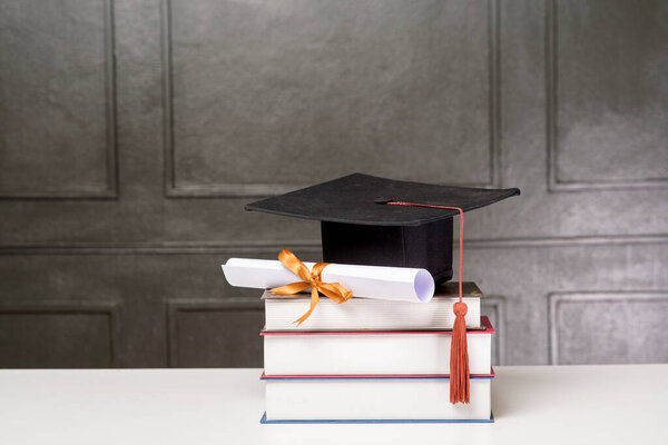 Graduation cap with books on white desk , Education background 