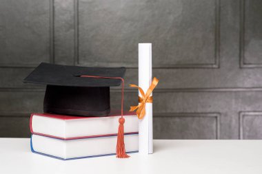 Mezuniyet şapkası, beyaz masada kitaplar, eğitim geçmişi. 