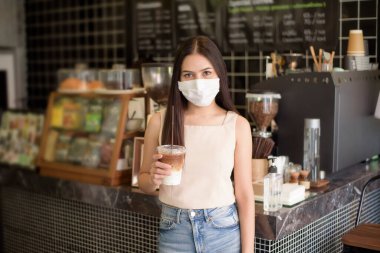 Kahve dükkanında maske takan güzel bir kadının portresi. 