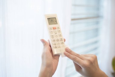 Kadın evde uzaktan kumandayı temizliyor. 