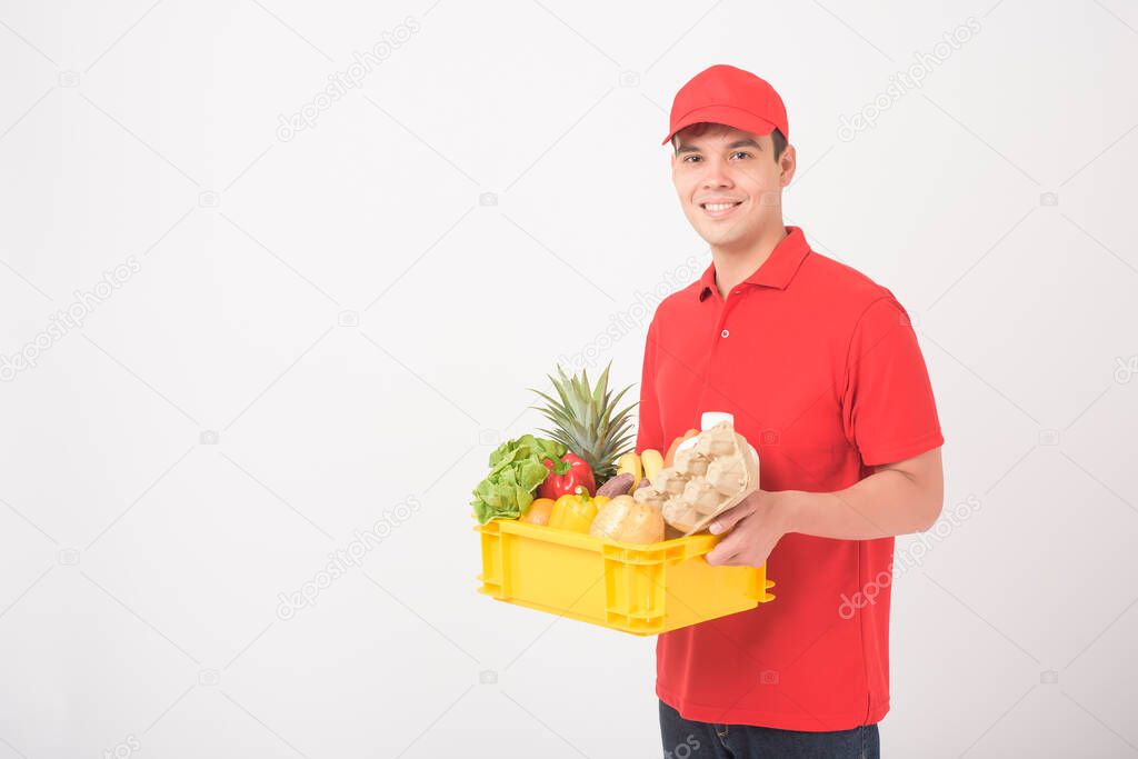 Portrait of a man in red uniform is holding fresh food in plastic box on white background,  home delivery concept 