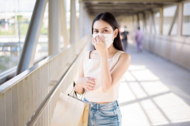 Yüzü maskeli genç kadın şehir dışında duruyor. 