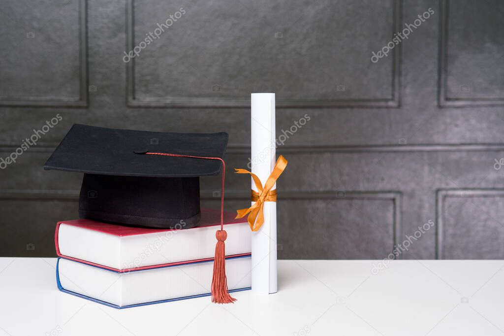 Graduation cap with books on white desk , Education background 