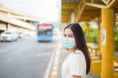Otobüs durağında güzel bir kadın maske takıyor. 